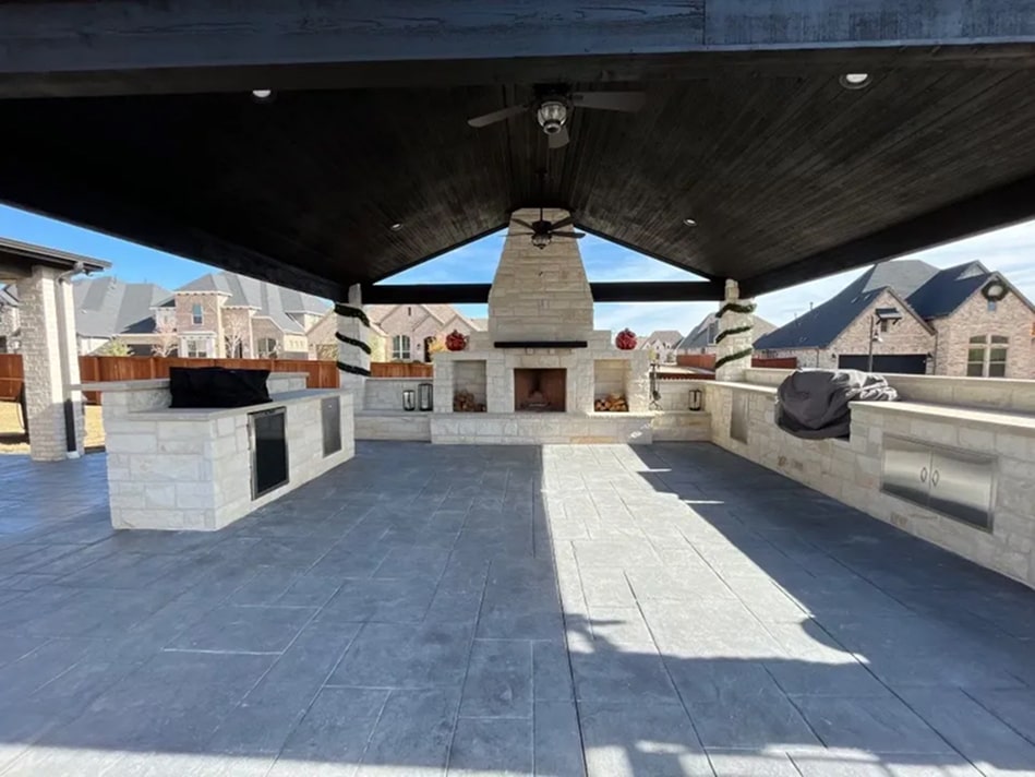 Covered patio area with grills, fireplace, and fans in a large stone area.