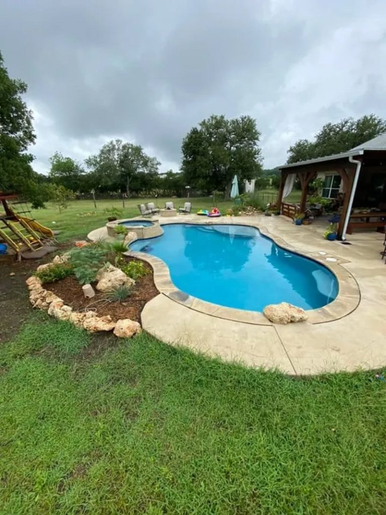 pool on the side of the house, seen with hot tub, loungers, and a playground off to the left.